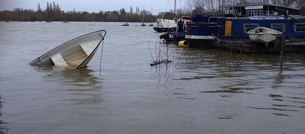 Small boat half-sunk in the flooded Thames