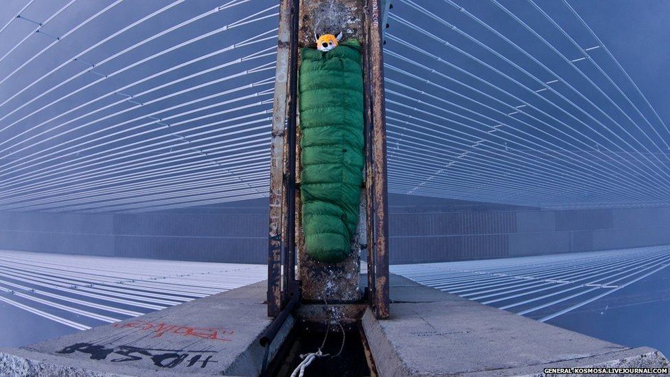 Explorer in a sleeping bag on top of a bridge.