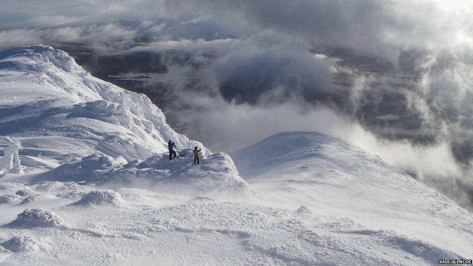 Two walkers take in the view from the summit of Meall a Bhuiridh in Glencoe this winter