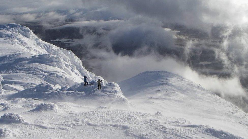 Two walkers take in the view from the summit of Meall a Bhuiridh in Glencoe this winter