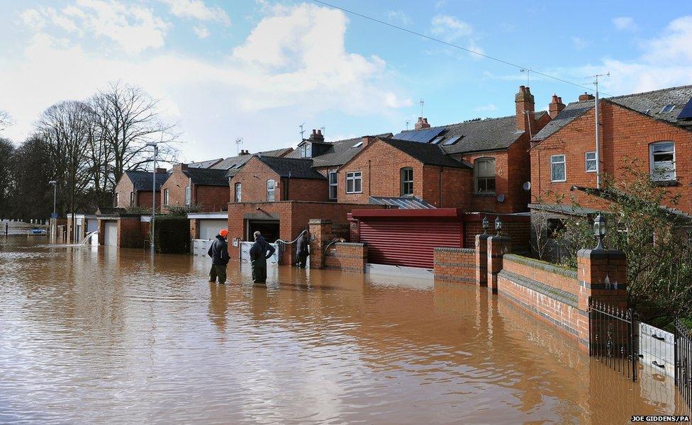 Residents of Waterworks Road in Worcester wade through the floodwater outside their home