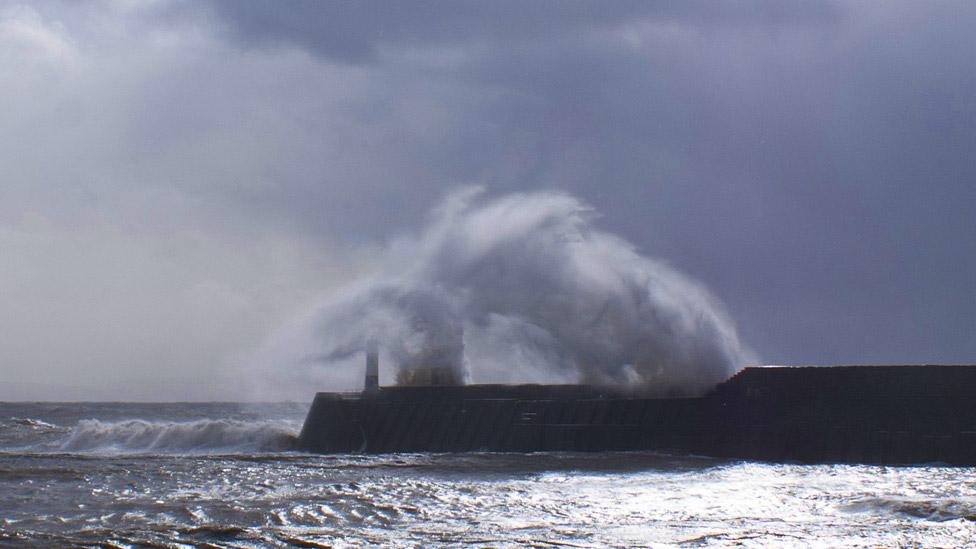 A wave leaps over Porthcawl lighthouse