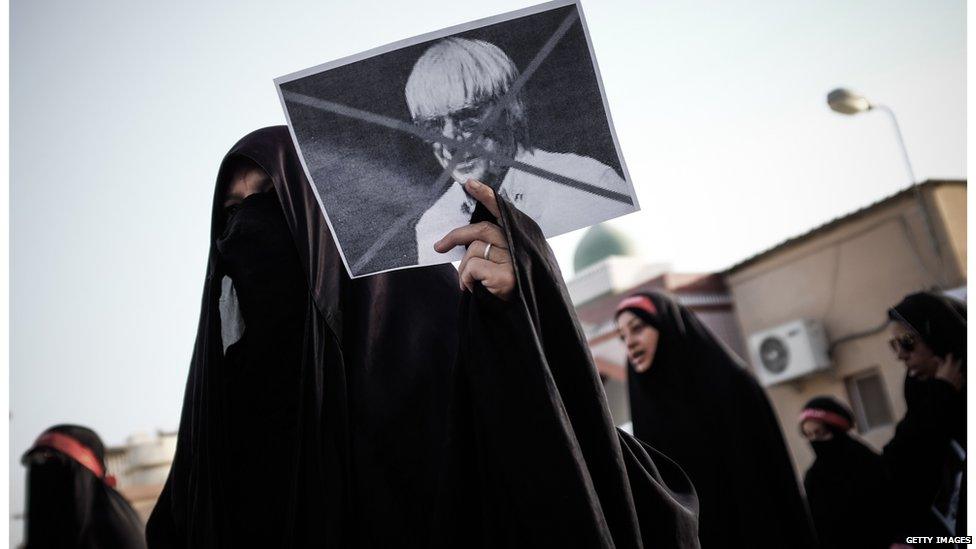 A Bahraini woman holds a cross marked picture of Formula One boss, Bernie Ecclestone, during a protest against the upcoming Bahrain Formula One Grand Prix