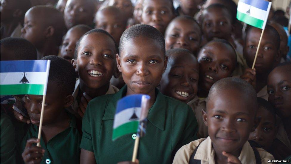 School children wave the national flag to welcome the Queen's baton as it arrives in Maseru, Lesotho.