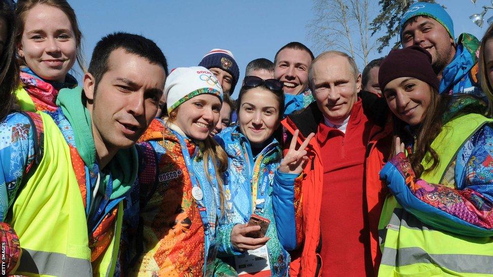 Russia's President Vladimir Putin poses for a photo with volunteers during the men's cross-country 4 x 10 km relay event at the 2014 Sochi Winter Olympics on February 16, 2014.