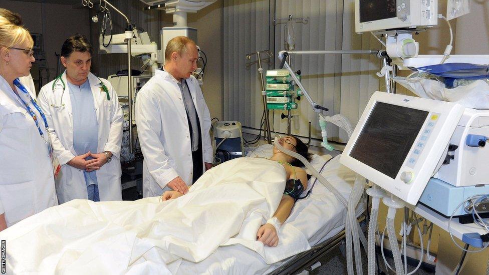 President Vladimir Putin (2nd R) visits Russian freestyle skier Maria Komissarova in a hospital in Sochi on February 15, 2014. 23-year-old Maria Komissarova sustained a broken back in a fall while training on the ski-cross course during the Sochi 2014 Winter Olympic Games .