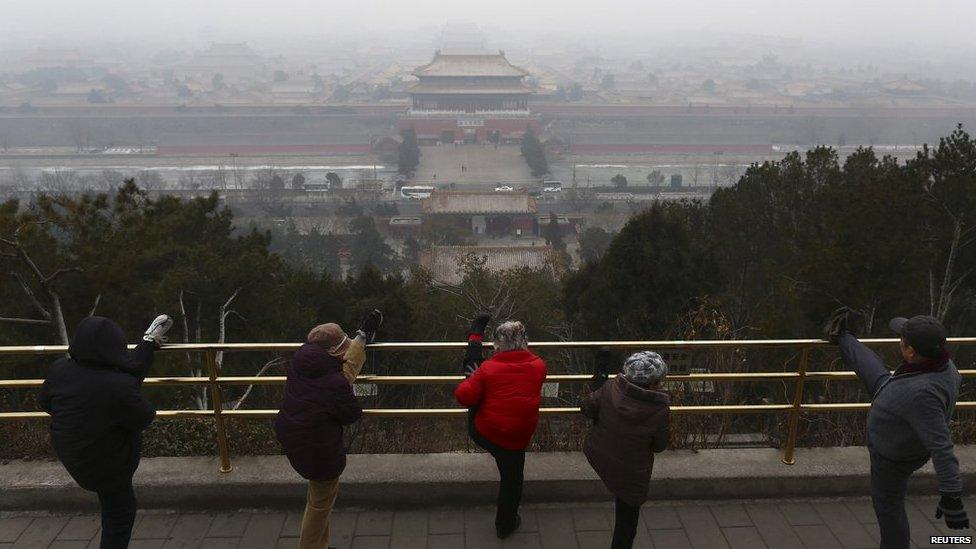 Residents stretch their legs during morning exercises on the top of Jingshan Park near the Forbidden City on a hazy day in Beijing on 21 February 2014