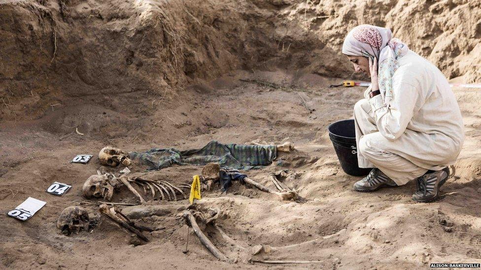 A student studies the human remains in the grave