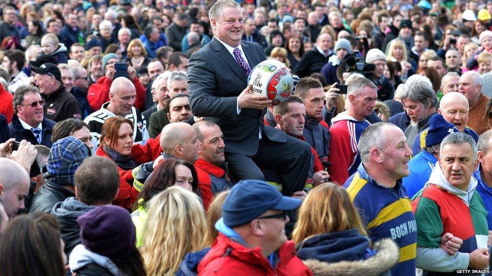 Shrovetide ball being carried through Ashbourne by local businessman Stuart Lees