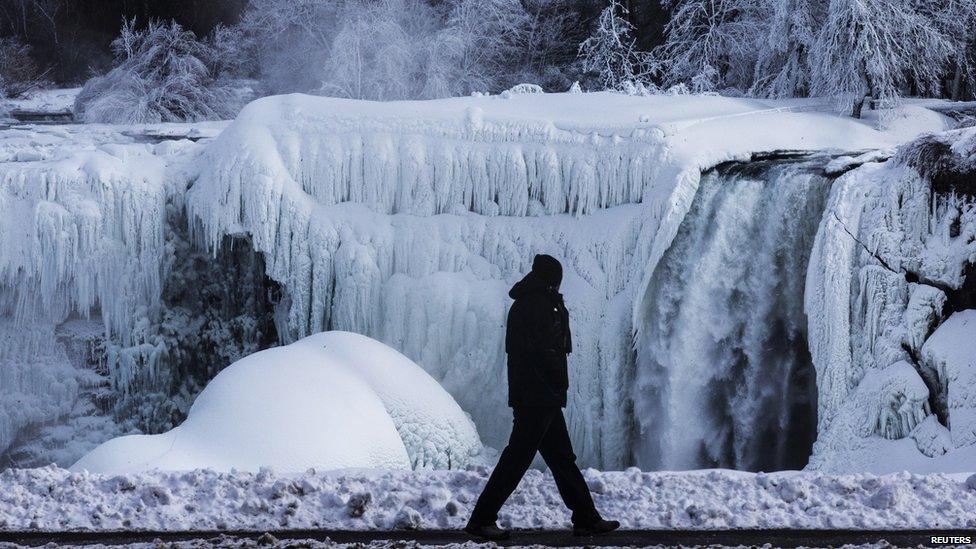 A man walks in front of the partially frozen American side of the Niagara Falls on during sub-freezing temperatures in Niagara Falls, Ontario.