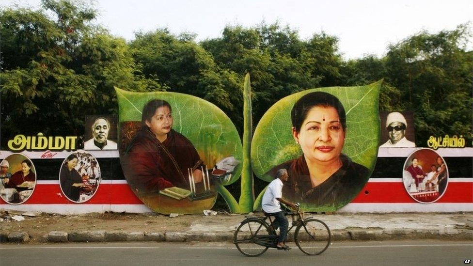 A cyclist rides past pictures of Tamil Nadu state chief minister and All India Anna Dravida Munnetra Kazhagam (AIADMK) leader Jayaram Jayalitha on the party symbol, two leaves displayed on a wayside in Chennai.