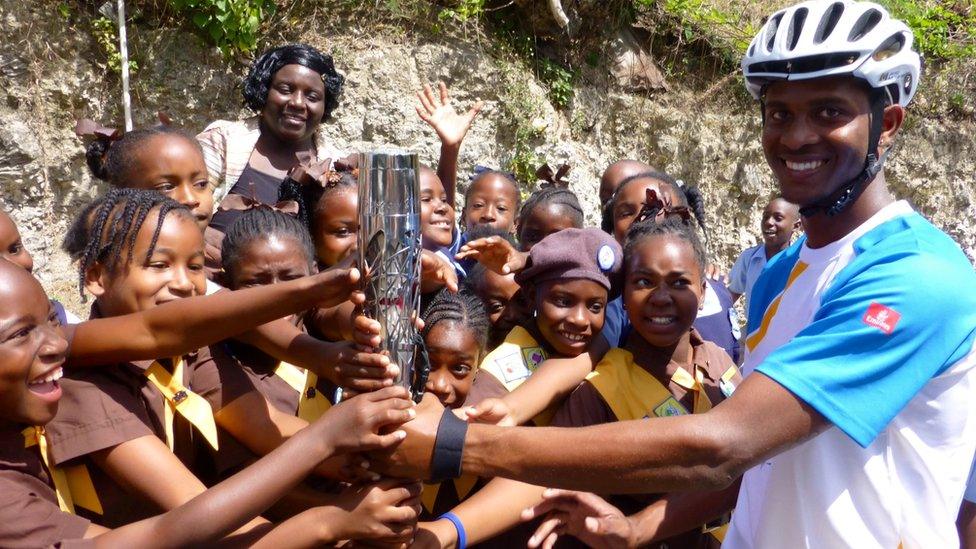 Barbados Cycling Team member Javed Mounter holds the Queen's Baton with a group of Brownies in Barbados.