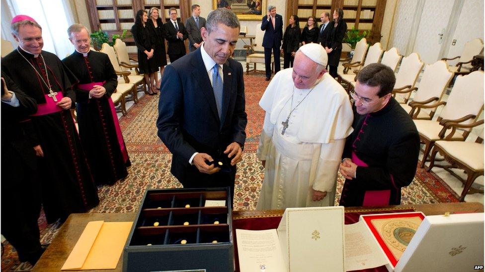 Pope Francis and US President Barack Obama exchanging gifts, with US and Church officials standing around