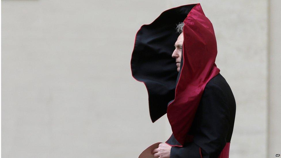 A gust of wind blows the mantle of Archbishop George Gaenswein, prefect of the papal household and former personal secretary of Pope Benedict XVI, as he waits for the arrival of President Barack Obama