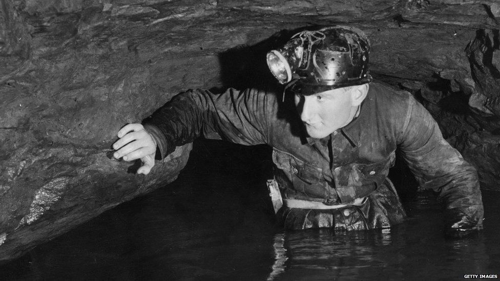 Caver John Buxton wades through limestone caves at Speedwell Water, Peak Cavern, in the Peak District, Derbyshire, circa 1960