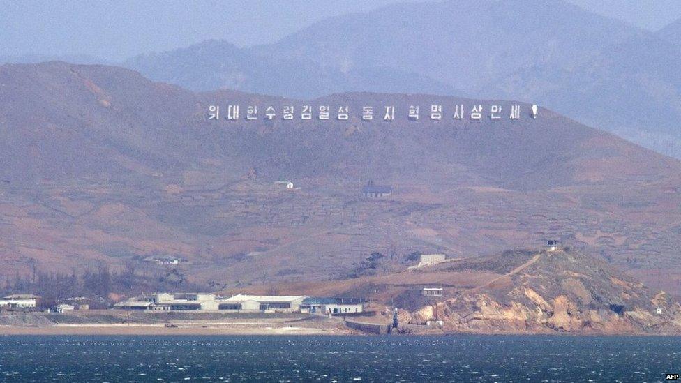 The seafront of North Korea's west coast with signs reading "Long live Great leader Kim Il-Sung and his revolutionary ideology!", is seen from the South Korea-controlled island of Yeonpyeong near the disputed waters of the Yellow Sea on 14 April 2013