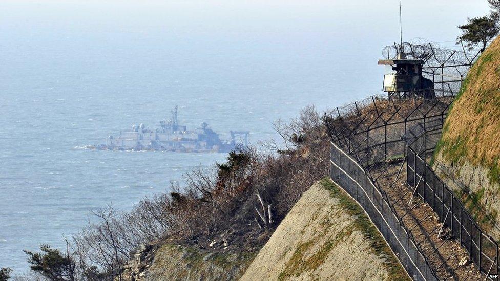 A South Korean military guard post is seen as a Navy MSB (Movement Sea Base) floats in the background at the South Korea-controlled island of Yeonpyeong near the disputed waters of the Yellow Sea on 13 April, 2013