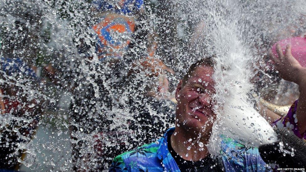 Man gets sprayed with water by an elephant