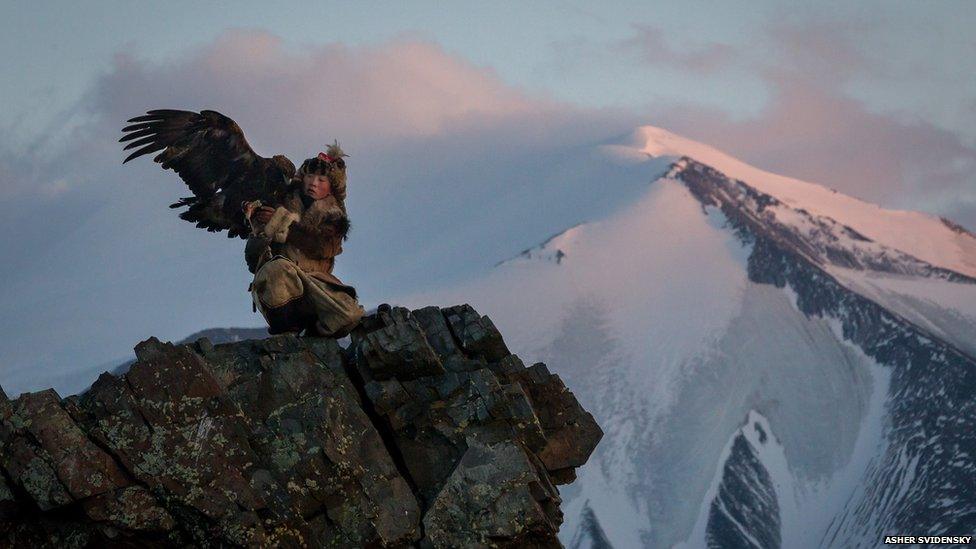 Bahak Birgen on a mountain cliff edge with his eagle
