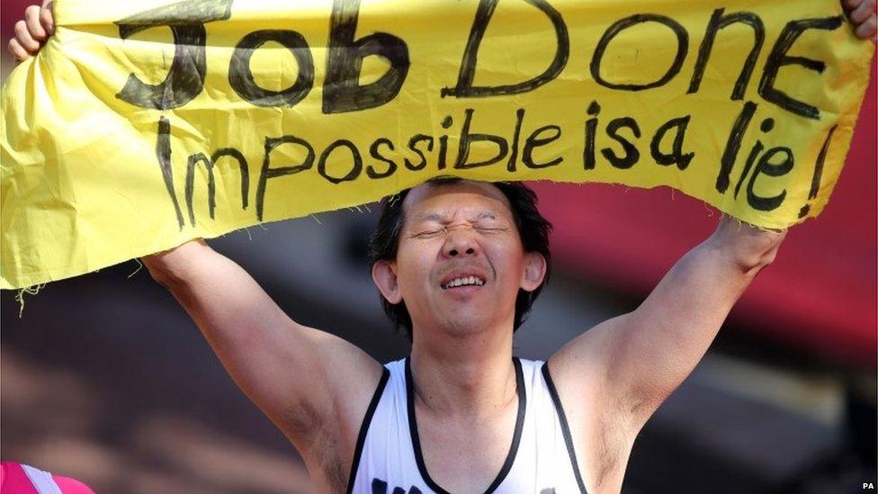 A runner holds up a sign after finishing the Virgin Money London Marathon on the Mall, London