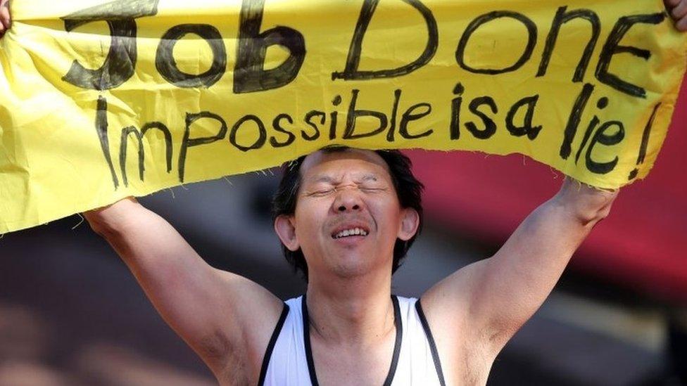 A runner holds up a sign after finishing the Virgin Money London Marathon on the Mall, London