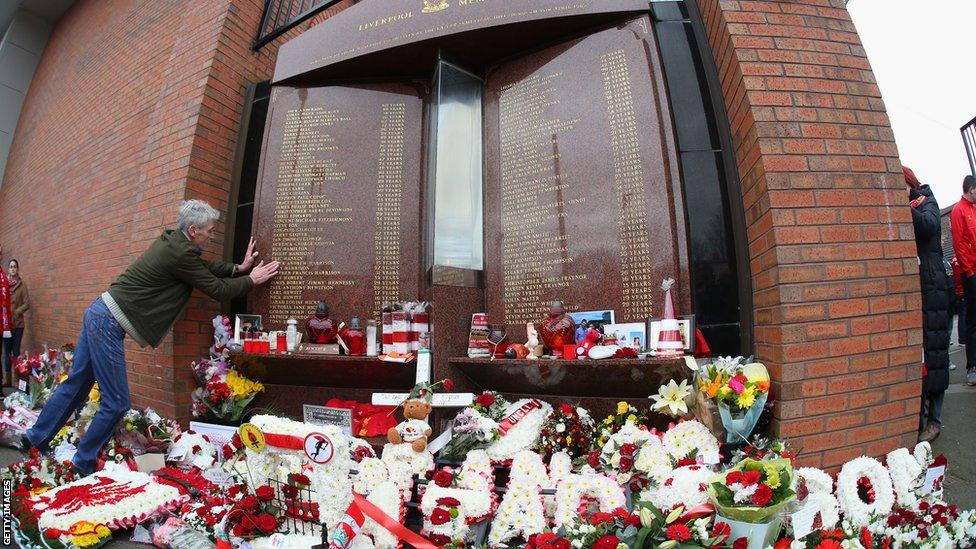 A fan looks for a name on the Hillsborough memorial at Anfield