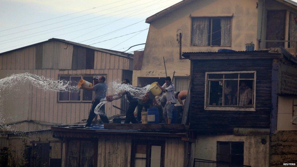 Residents throw water on a fire in Valparaiso on 13 April 2014