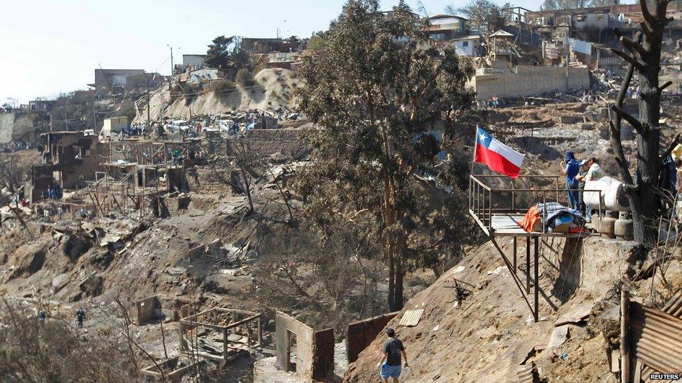 Residents survey damage after a fire burned several neighbourhoods in the hills in Valparaiso, April 14, 2014.