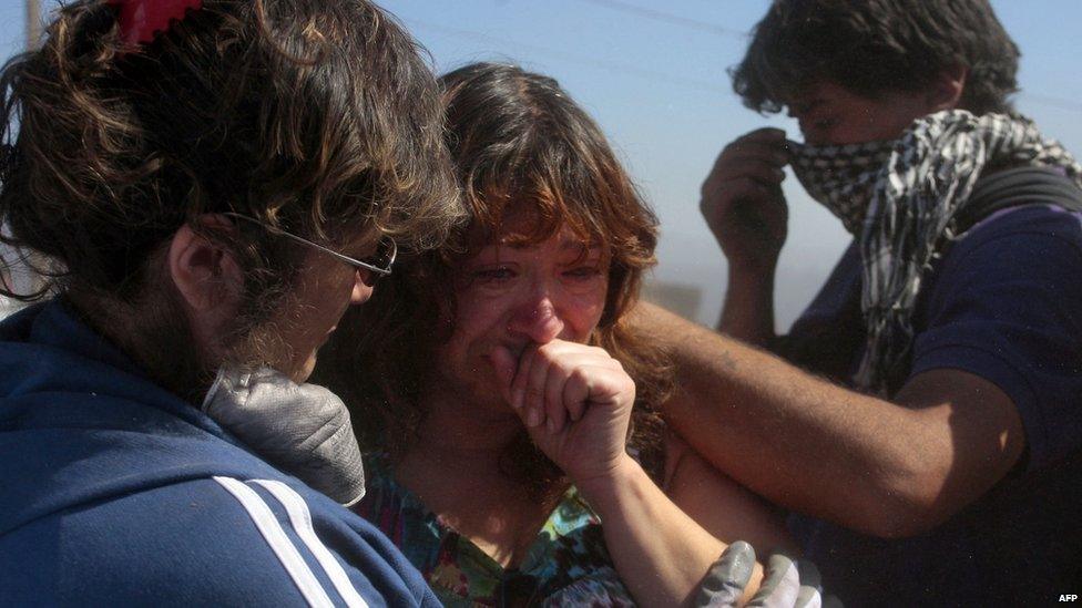 A woman is comforted by relatives after a huge fire devastated her home in Valparaiso, on April 14, 2014.