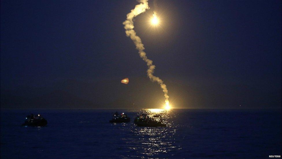 South Korea's coast guard shoot flares into the night sky as the search for passengers from the sinking ferry continues - 16 April 2014