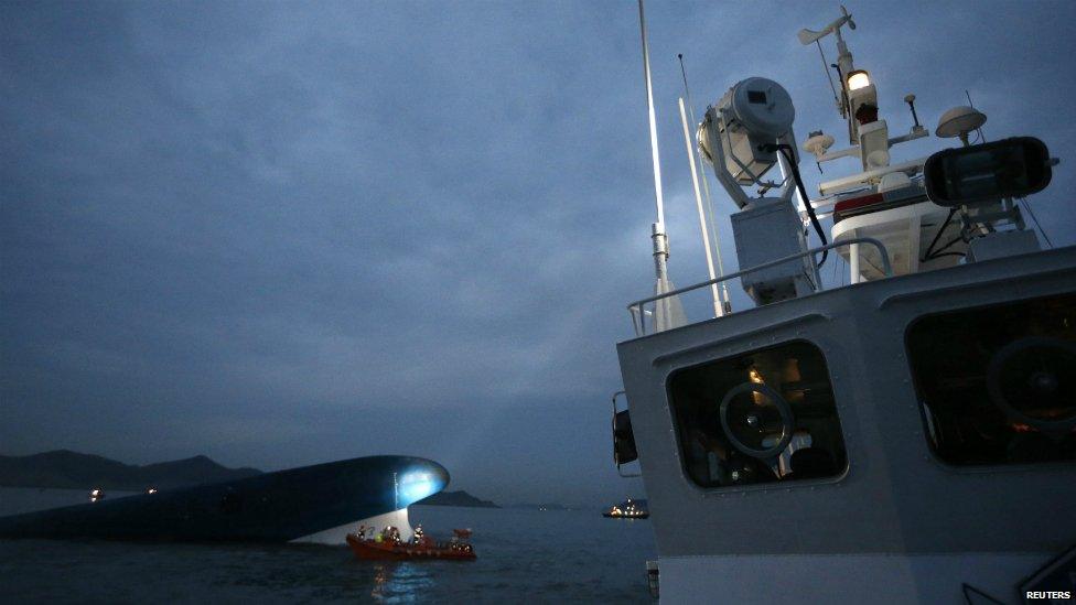 One of the boats involved in the search operation shines its spotlight on to the last part of the ferry left above the water - 16 April 2014