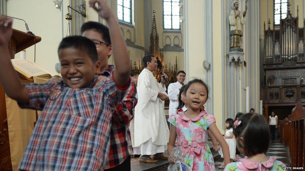 While these children sing and dance during a mass in Indonesia.