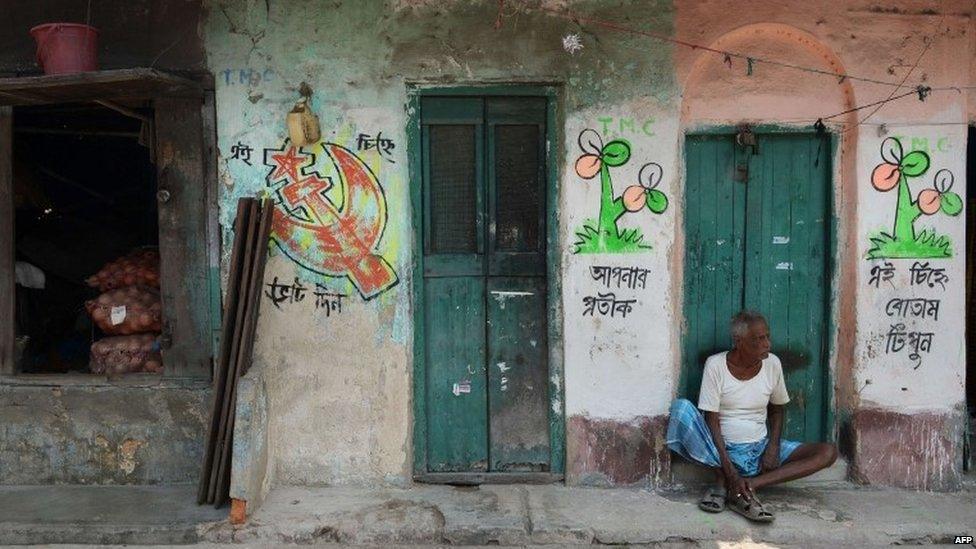 An Indian labour sits alongside graffiti in support of different political parties in Kolkata