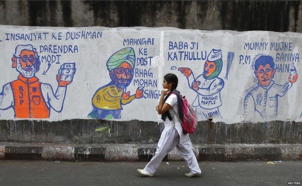 A school girl walks past a wall with graffiti depicting Indian politics in Calcutta.