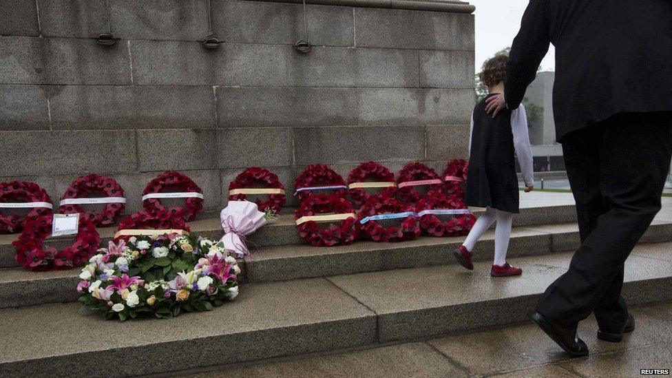 A father walks with his daughter past poppy wreaths during Anzac Day services at the Cenotaph in Hong Kong on 25 April, 2014