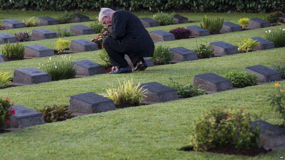 A visitor to the Jakarta War Cemetery places a poppy on a headstone following the ANZAC Day dawn service in Jakarta, Indonesia, on Friday, 25 April, 2014