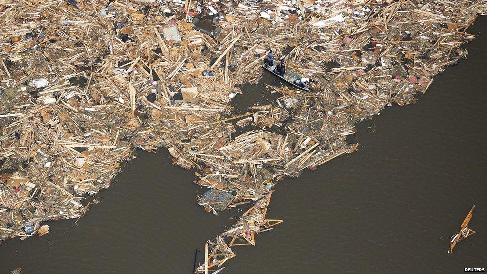 Men use boards as paddles as they search though the debris of what is left of homes in a lake in Vilonia, Arkansas on 28 April 2014.