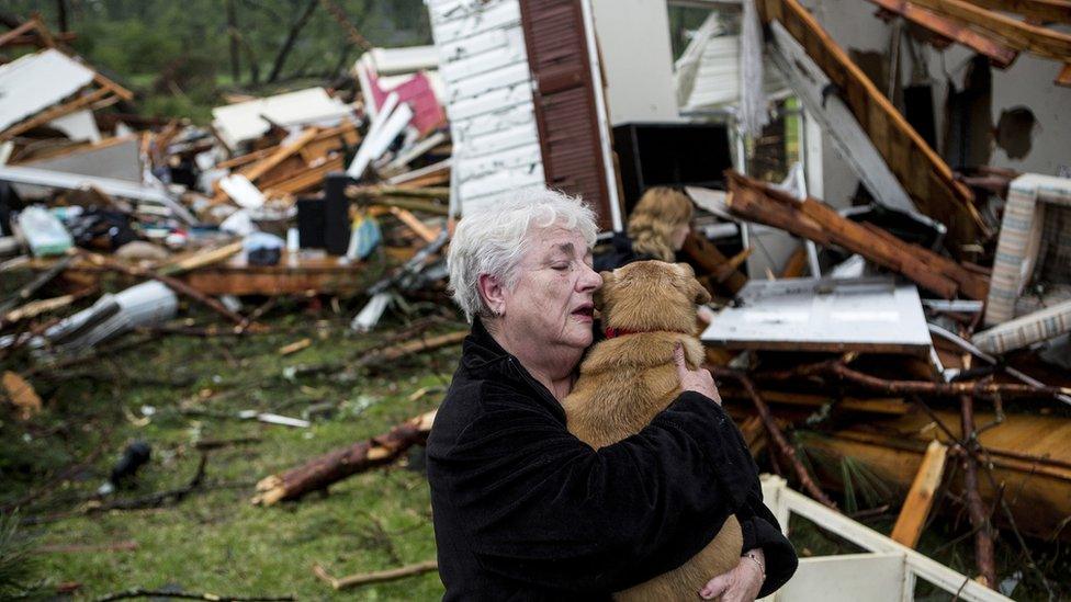 Constance Lambert embraces her dog after finding it alive when returning to her destroyed home in Tupelo, on 28 April