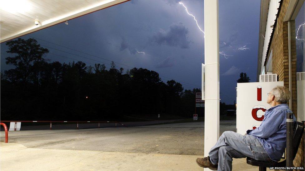 Jimmy Sullinger, sits and watches lightning as a storm approaches the gas station where he works on 28 April in Berry, Alabama.