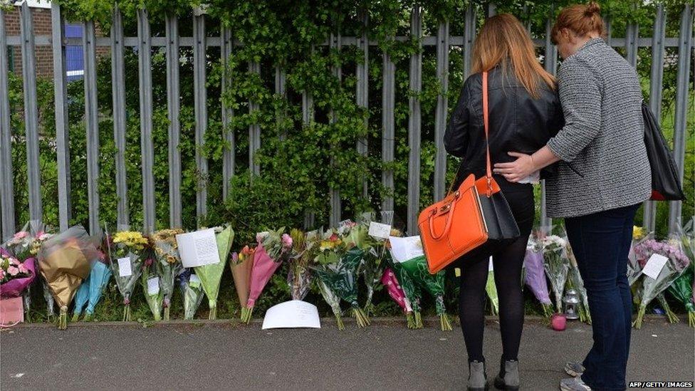 A woman and child look at floral tributes left at Corpus Christi Catholic College in Leeds