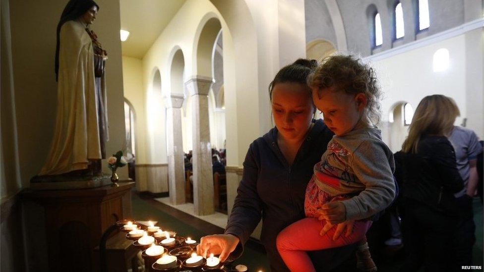 A woman and child light a candle in Corpus Christi Catholic Church after teacher Ann Maguire was fatally stabbed at Corpus Christi Catholic College in Leeds