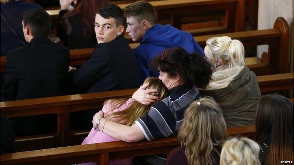 A child is comforted in Corpus Christi Catholic Church after teacher Ann Maguire was fatally stabbed at Corpus Christi Catholic College in Leeds