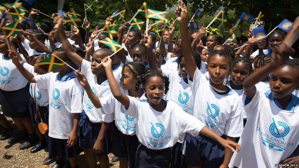 A group of young children all waving small Jamaican national flags.