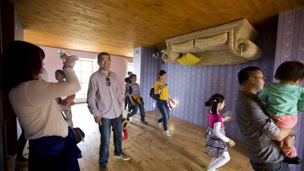 Woman takes photo in upside-down house.
