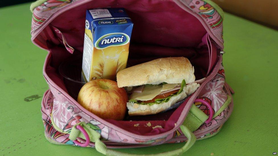 The lunch consists of a sandwich of ham, cheese, tomato and lettuce, a boxed oatmeal drink, and an apple.