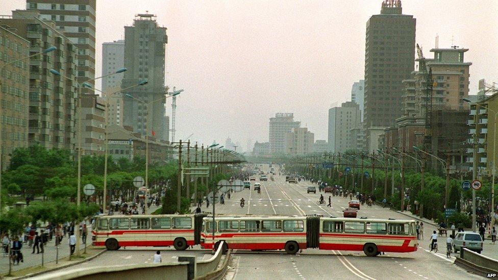 Two city buses block Jianguomen Avenue, the main street to Tiananmen Square, on 21 May 1989