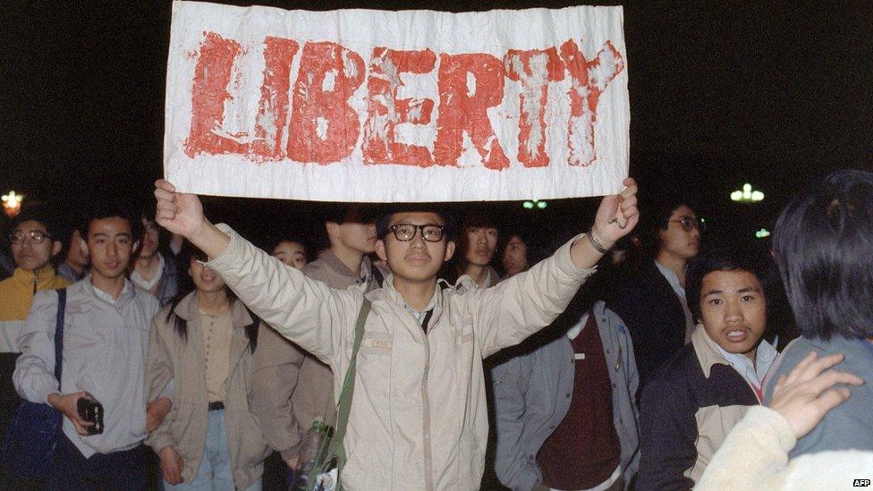 A student displays a banner with one of the slogans chanted by the crowd in Tiananmen Square on 22 April 1989