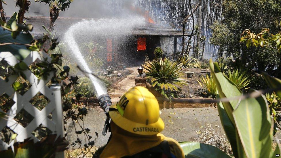 A fire fighter poured water onto a fully engulfed home in Carlsbad, California, on 14 May 2014