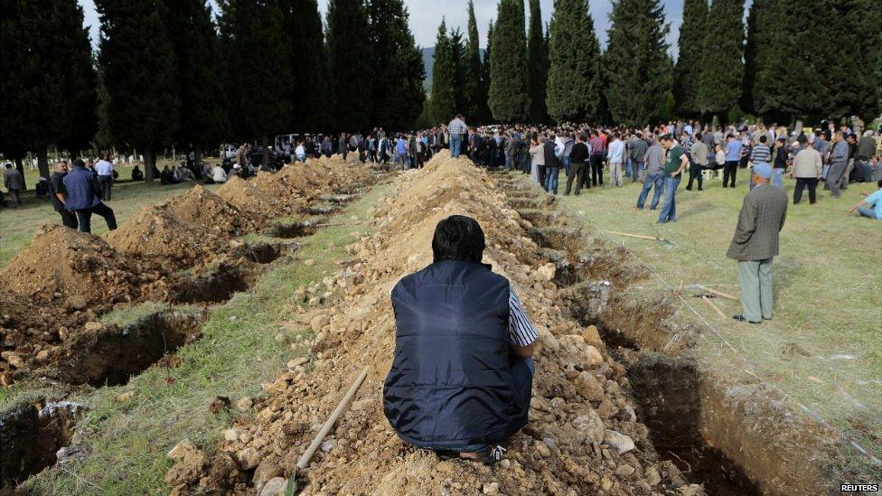 A man sits near graves during the funeral of a miner who died in disaster in Soma - 14 May 2014