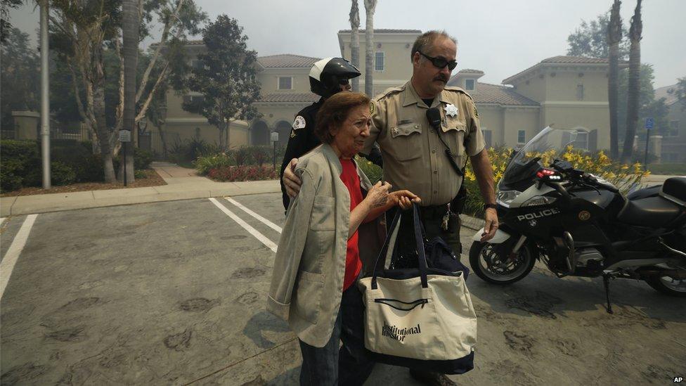 A woman was evacuated from her building during a wildfire in Carlsbad, California, on 14 May 2014